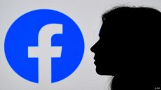 (FILES) In this August 17, 2021, file photo illustration, a person looks a Facebook App logo displayed on the background in Arlington, Virginia. - Facebook announced over $9 billion in quarterly profits on October 25, 2021, hours after a US news collective published a deluge of withering reports arguing the company prioritizes its growth over people's safety. (Photo by OLIVIER DOULIERY / AFP)
